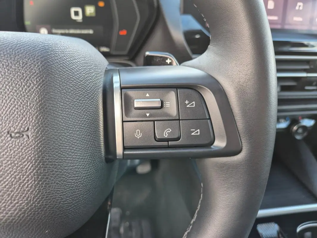 Gros plan sur les commandes au volant cuir noir du Citroën C5 X 2024, avec boutons de volume et appel intégrés.