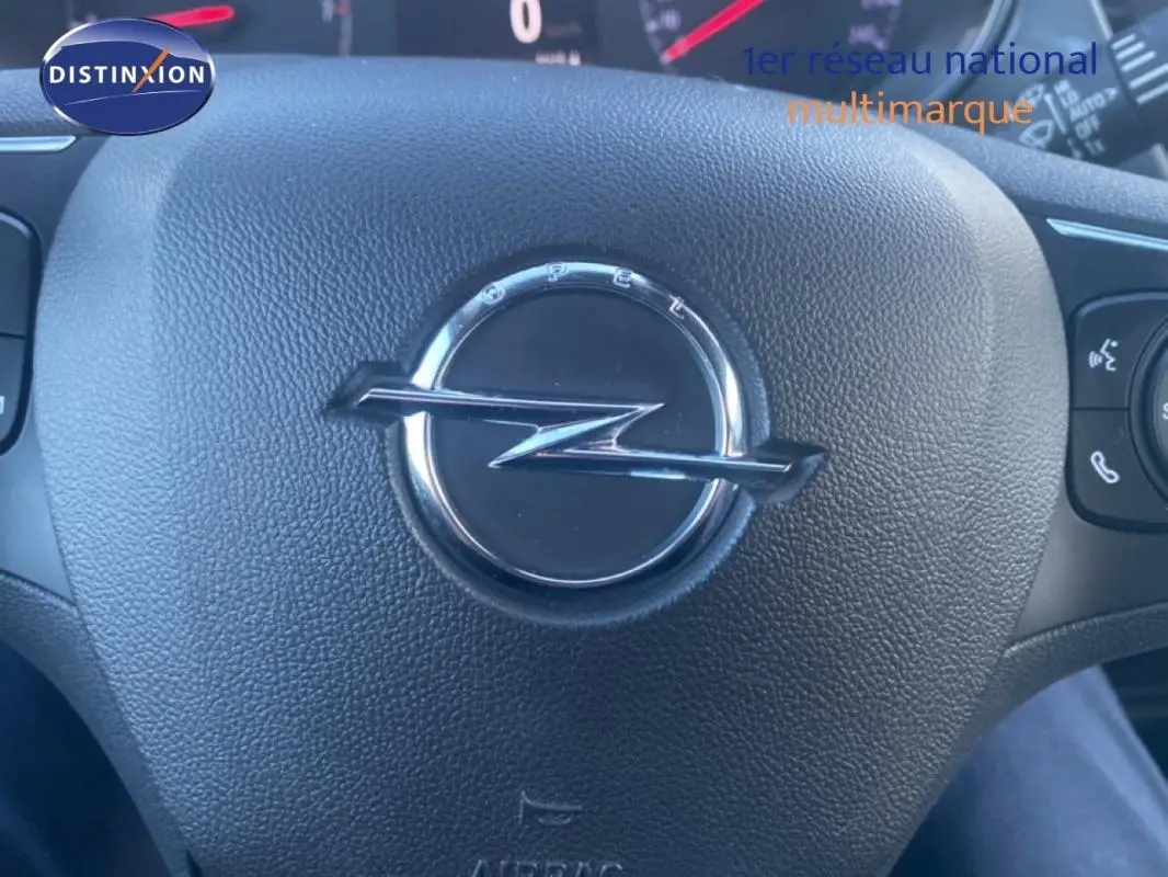 Gros plan sur le volant cuir noir de l'Opel Crossland 2022 avec logo Opel central et commandes multifonctions visibles.