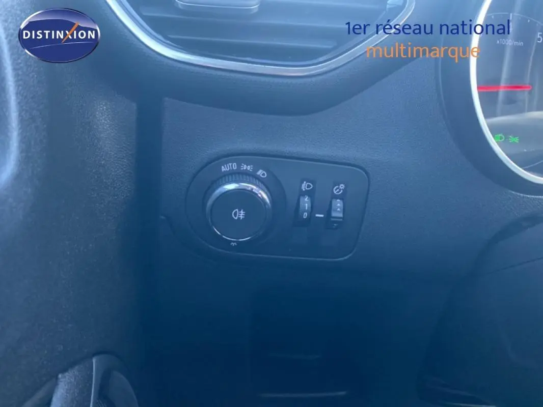 Gros plan sur la commande des feux et réglages d’éclairage côté gauche du tableau de bord d’un Opel Crossland gris foncé 2022.