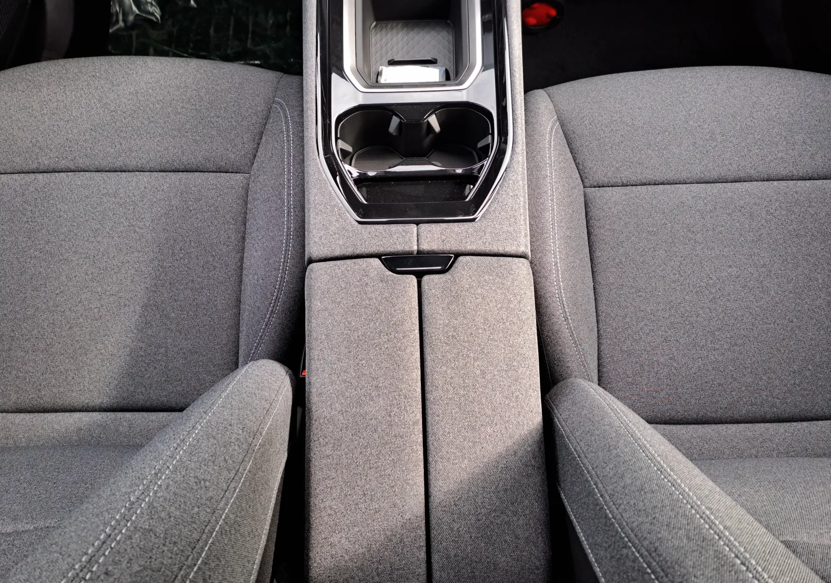 Vue rapprochée de la console centrale et des sièges en tissu gris du Renault Austral 2025 hybride.