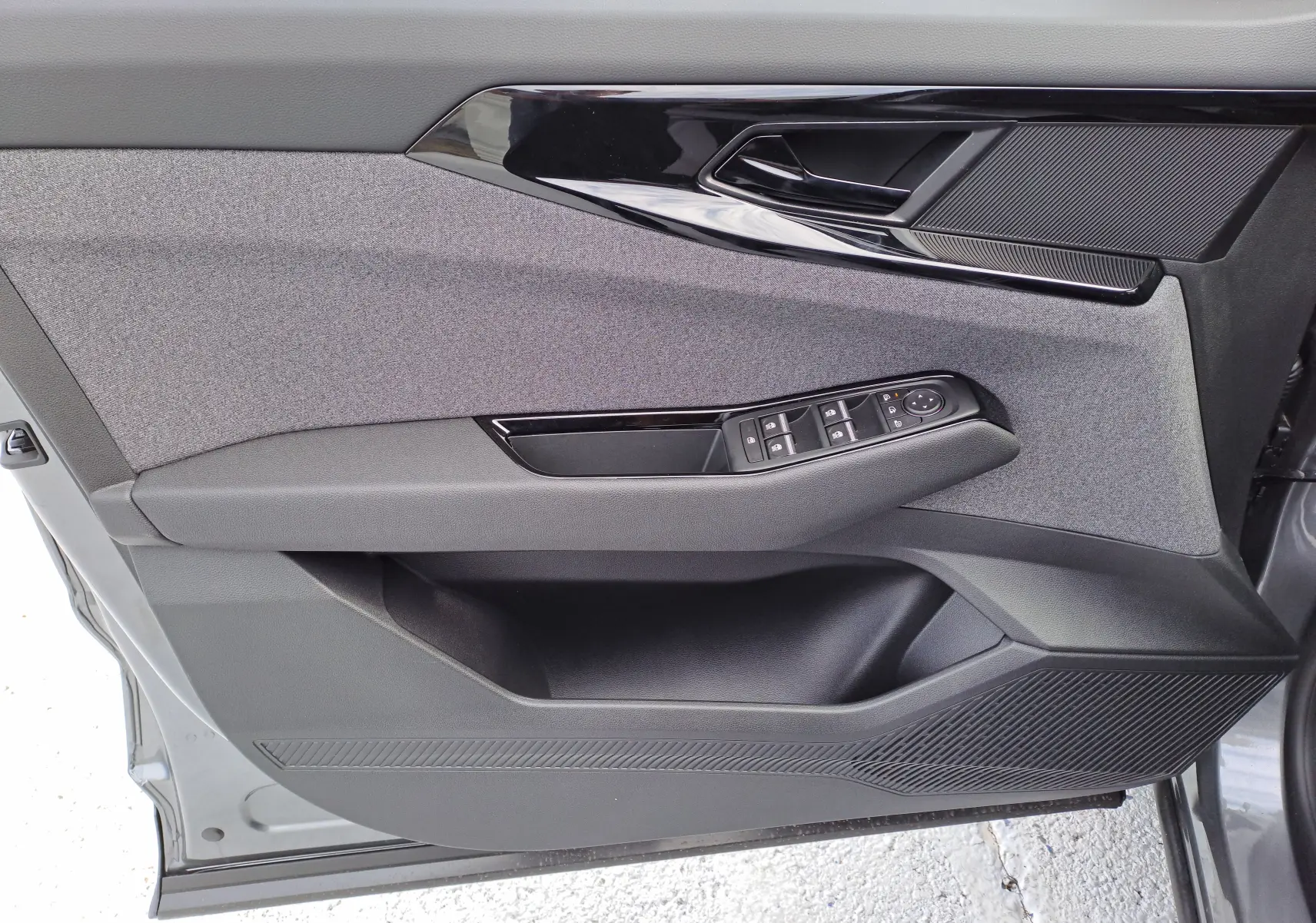 Vue rapprochée de la porte avant gauche du Renault Austral gris schiste, avec commandes électriques et garniture tissu noir.