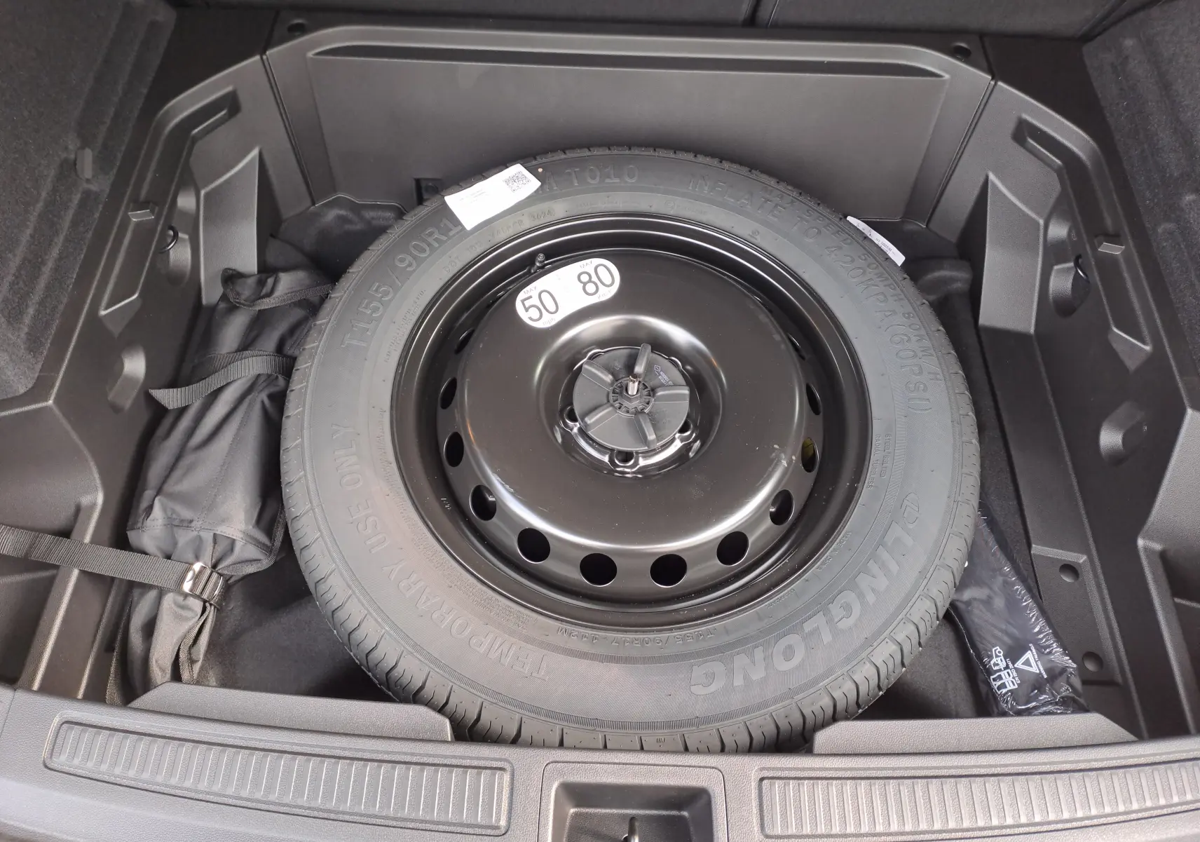 Vue plongeante sur la roue de secours noire dans le coffre du Renault Austral gris schiste 2025.