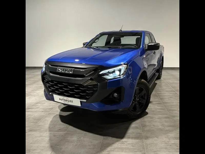 Pick-up Isuzu D-MAX 2025 en Biarritz Blue Metallic, vu de face à 3/4 gauche avec phares LED allumés.