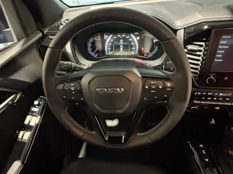 Vue rapprochée du volant multifonction noir de l'Isuzu D-MAX 2025 avec tableau de bord numérique et écran tactile latéral.