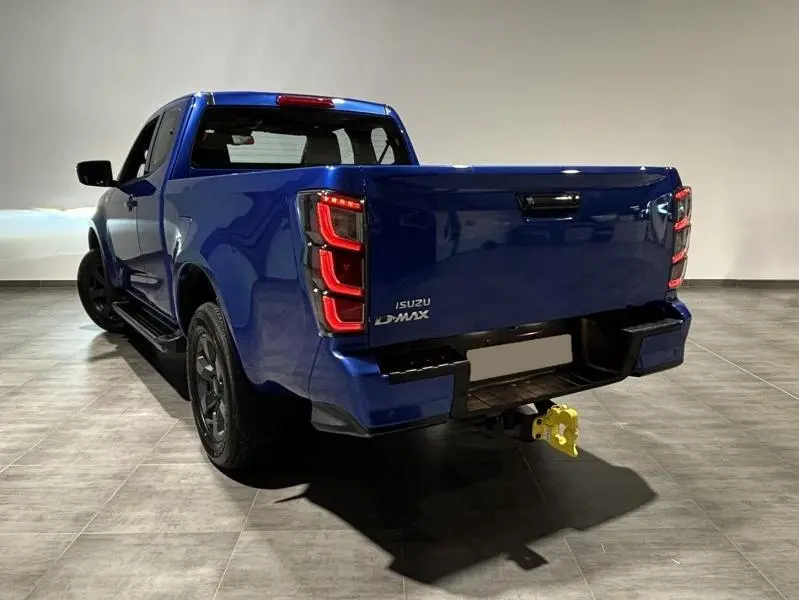 Vue 3/4 arrière droite d'un pick-up Isuzu D-MAX 2025 en bleu Biarritz métallisé avec feux arrière LED distinctifs.