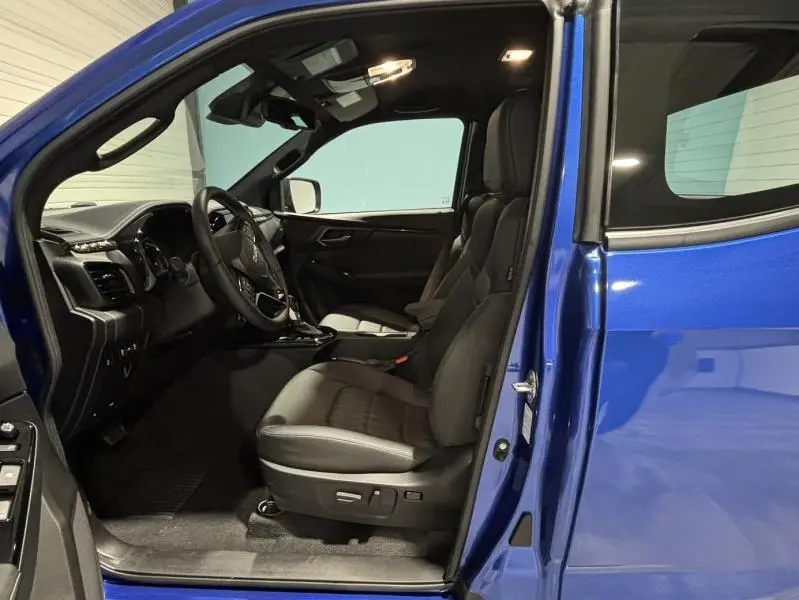 Vue intérieure côté conducteur de l'Isuzu D-MAX 2025 bleu Biarritz, sièges cuir e-Tech et tableau de bord moderne.