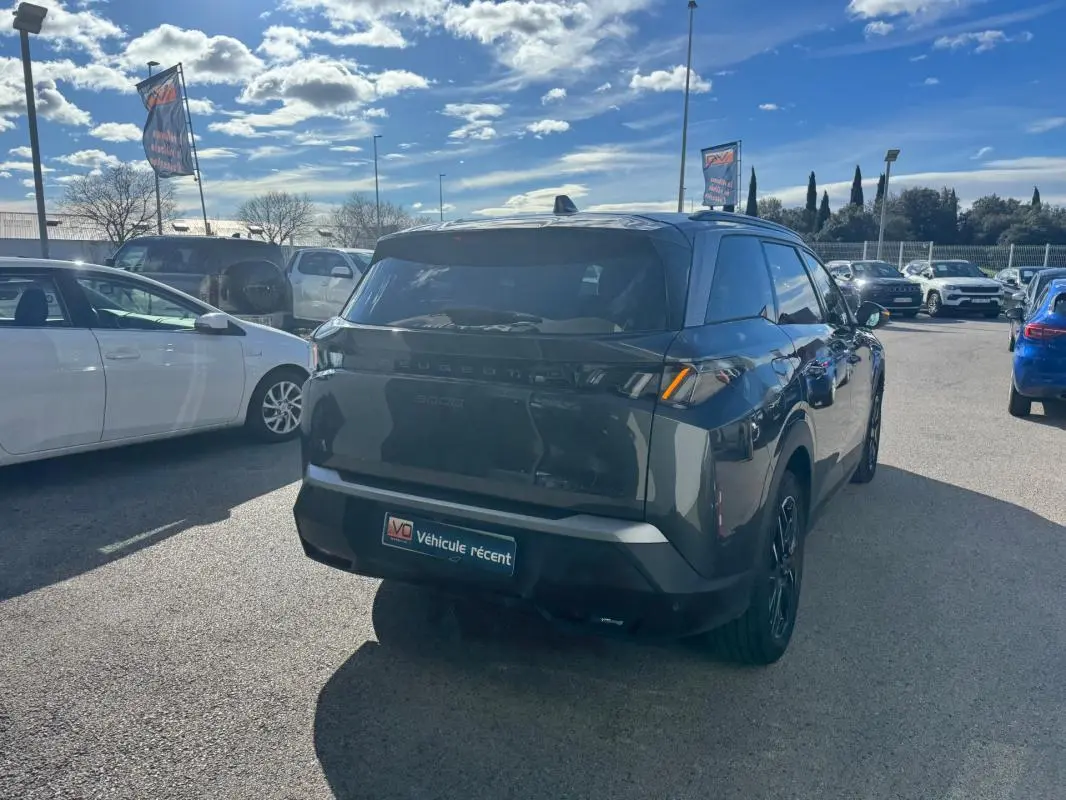 Vue 3/4 arrière droite d’un Peugeot 5008 gris 2025 avec feux arrière allumés et jantes alliage noires.