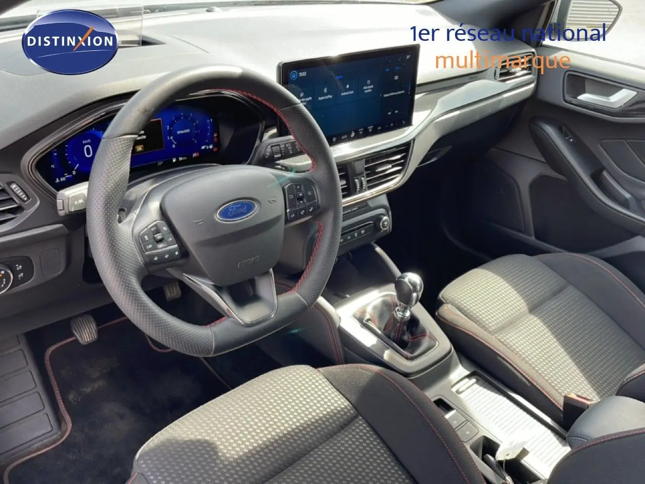 Vue intérieure de la Ford Focus SW 2023 montrant le volant, la console centrale avec boîte manuelle et les sièges tissu gris.