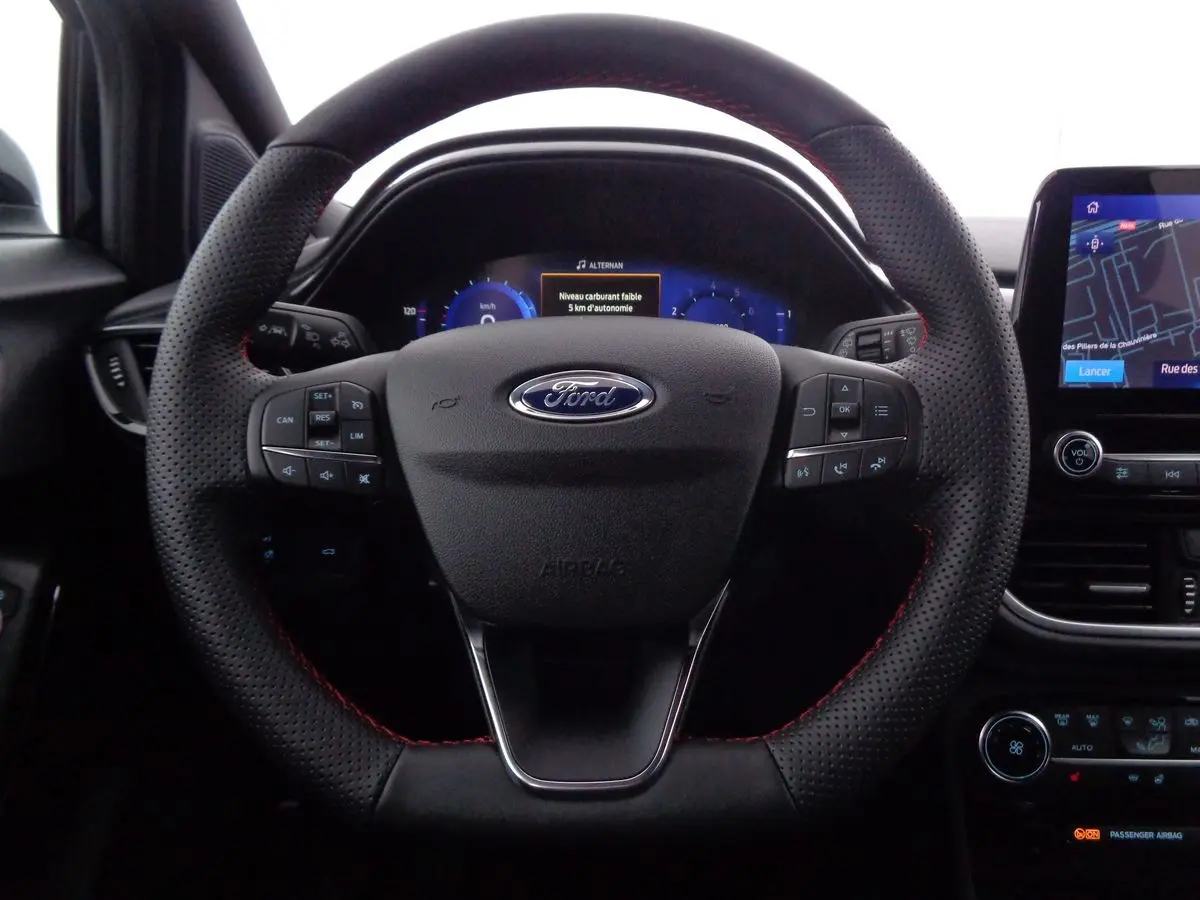 Vue rapprochée du volant en cuir noir avec surpiqûres rouges de la Ford Puma 2022, tableau de bord numérique et écran tactile visible.