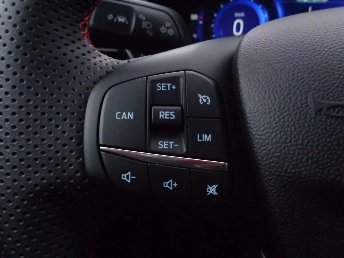 Gros plan sur les commandes de régulateur et volume au volant perforé noir du Ford Puma 1.0 EcoBoost MHEV 2022.