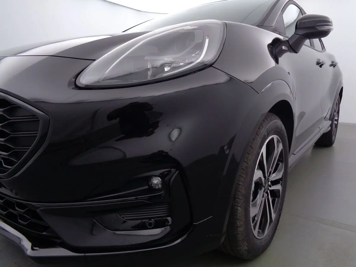 Gros plan sur l'avant droit noir agate métallisé du Ford Puma 1.0 EcoBoost MHEV 155ch ST-Line avec phares LED et jantes bi-ton.