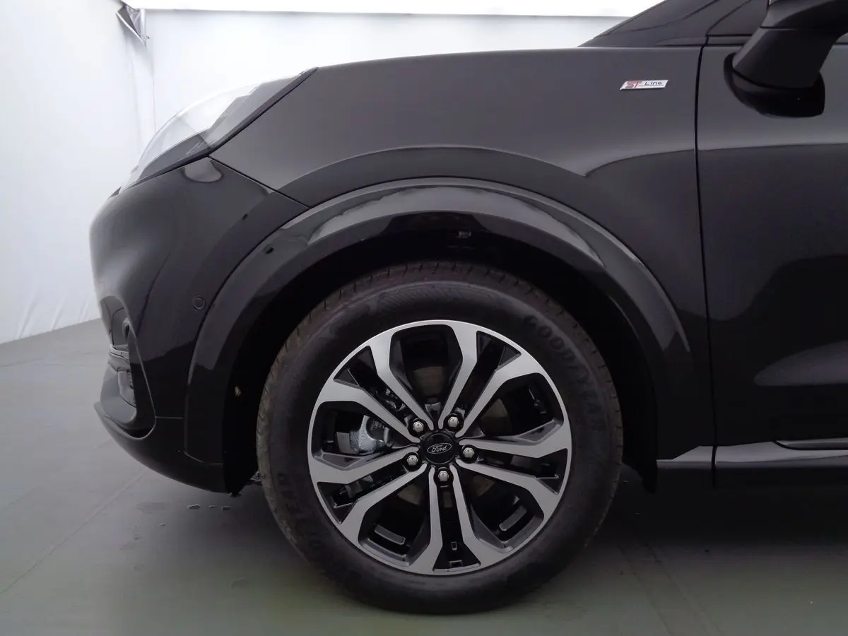 Gros plan sur la roue avant gauche et l'aile noire agate métal du Ford Puma 1.0 EcoBoost MHEV 155ch ST-Line.