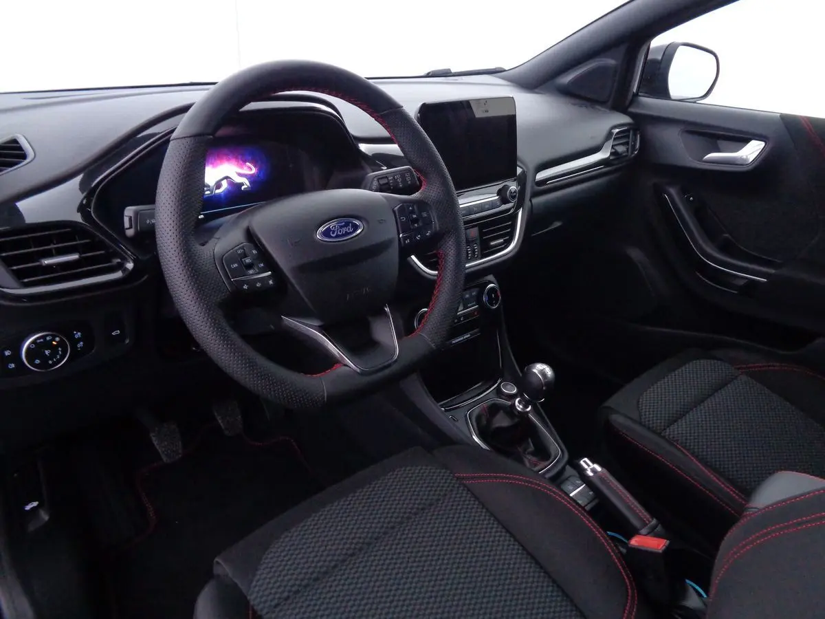 Intérieur de la Ford Puma 1.0 EcoBoost MHEV 2022, vue côté conducteur, sièges noirs avec surpiqûres rouges et volant multifonction.