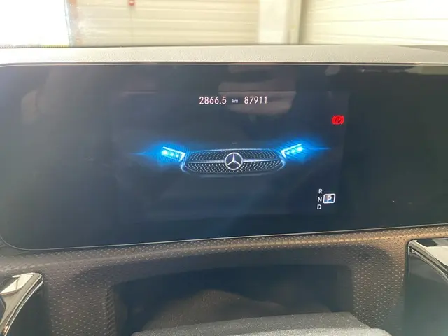 Écran digital du tableau de bord montrant le logo Mercedes avec phares bleus et compteur kilométrique de la CLA Shooting Brake noire.