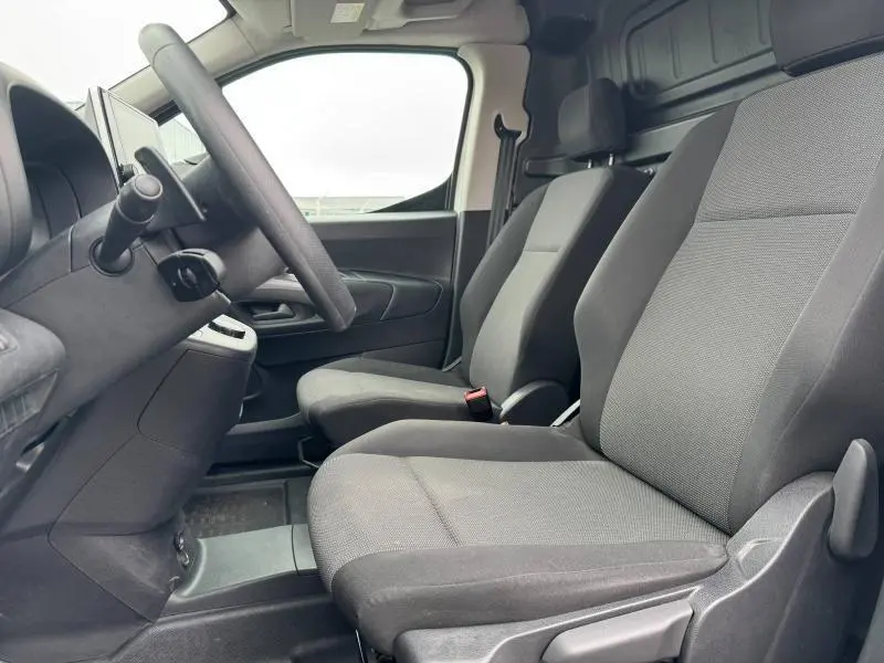 Vue intérieure côté conducteur du Citroën Berlingo Fourgon blanc Banquise, sièges tissu gris et tableau de bord noir.