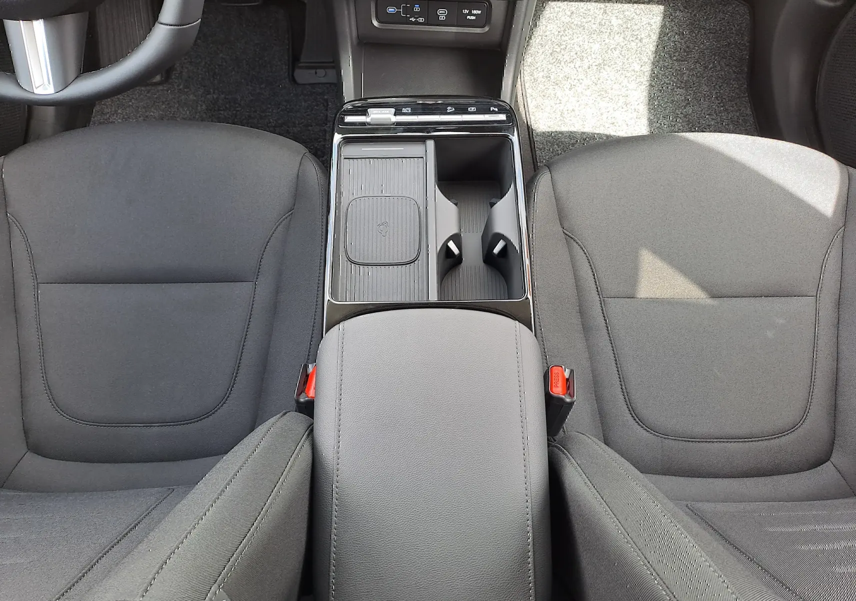 Vue plongeante sur la console centrale et les sièges avant noirs en tissu du Hyundai Tucson 2025 Ecotronic Grey.