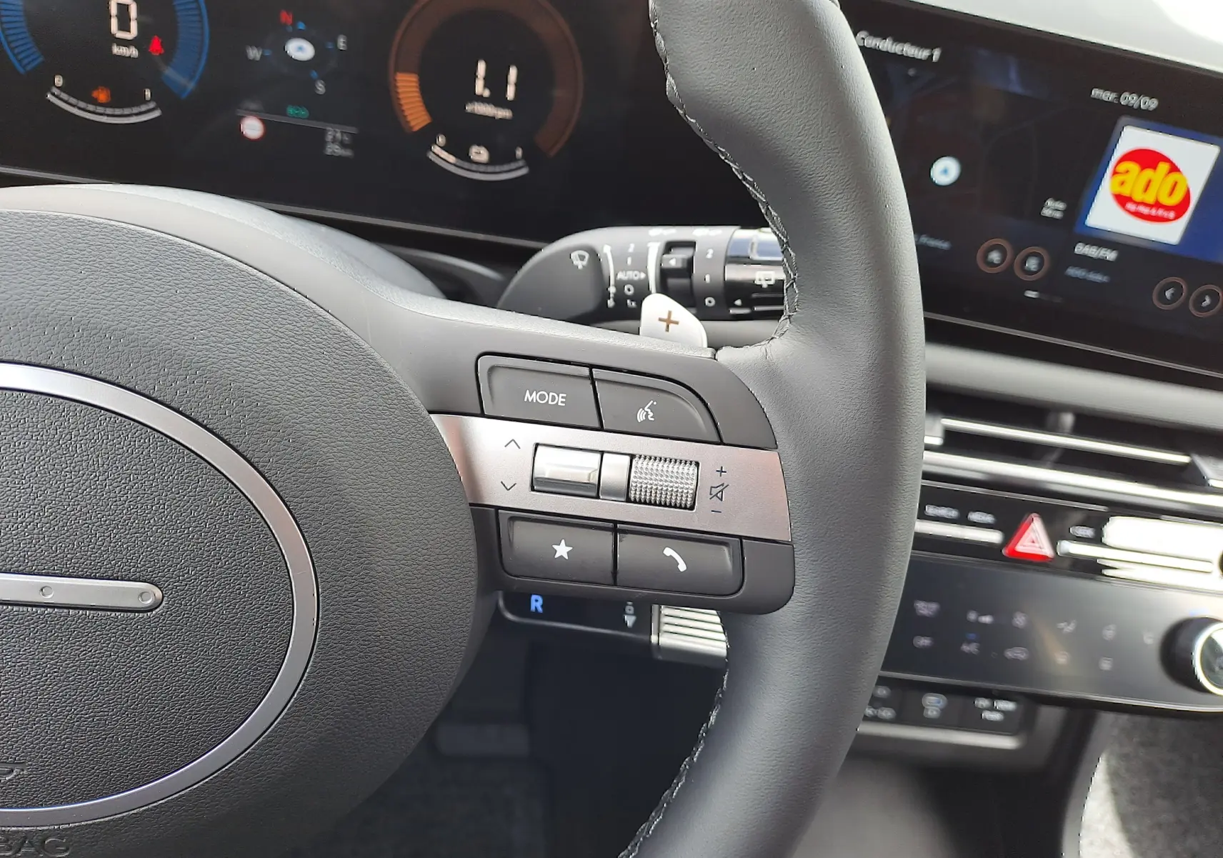 Gros plan sur le volant noir du Hyundai Tucson 2025 avec commandes intégrées et tableau de bord numérique en arrière-plan.