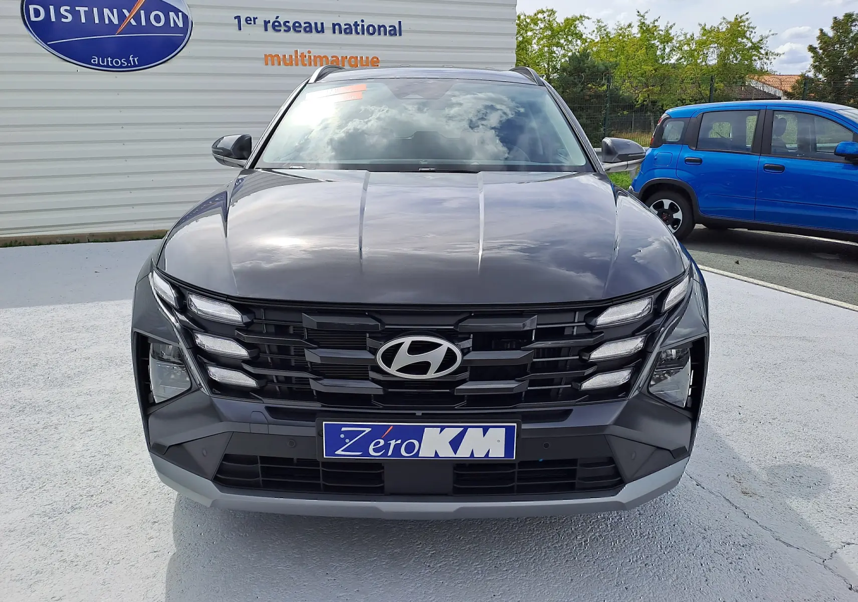 Vue frontale d'un Hyundai Tucson 2025 gris Ecotronic avec calandre noire et plaque "Zéro KM" visible.