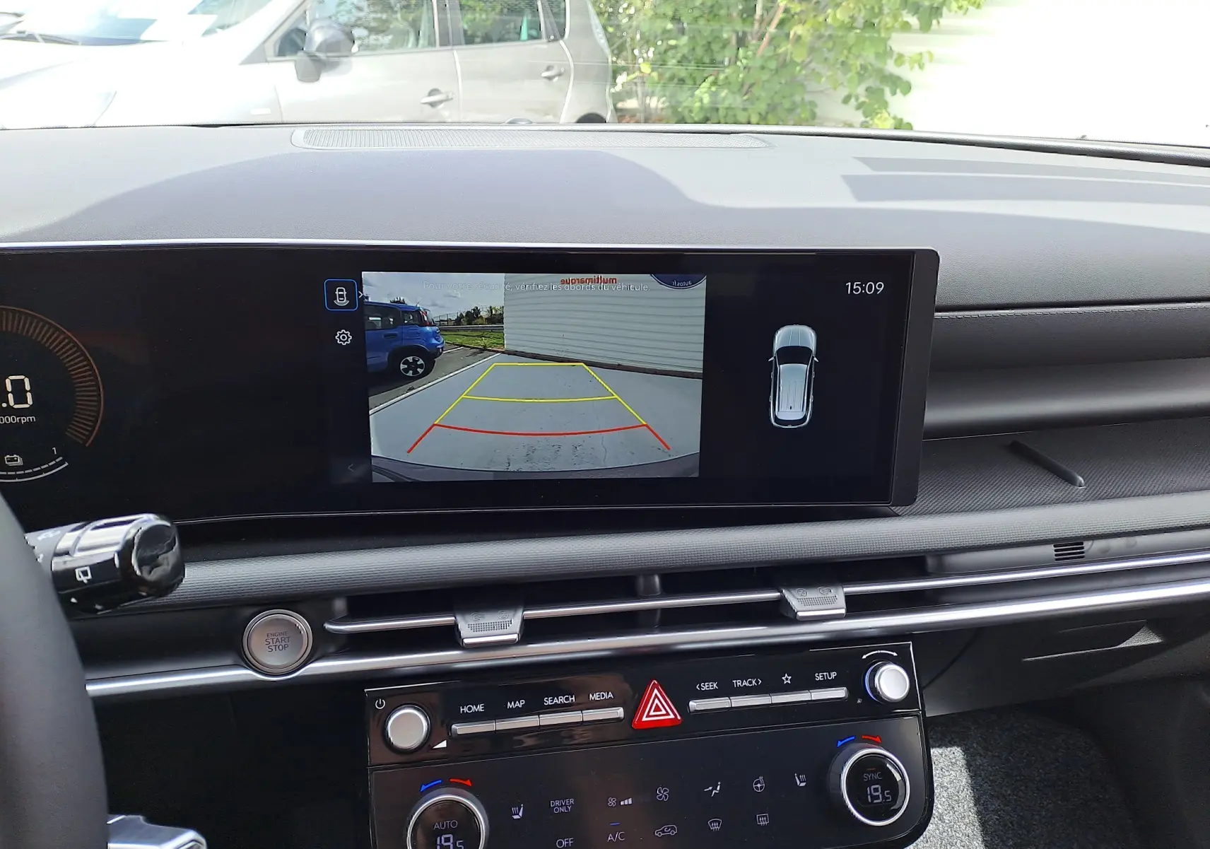 Vue intérieure du tableau de bord du Hyundai Tucson 2025 avec écran de caméra de recul et commandes climatisation.