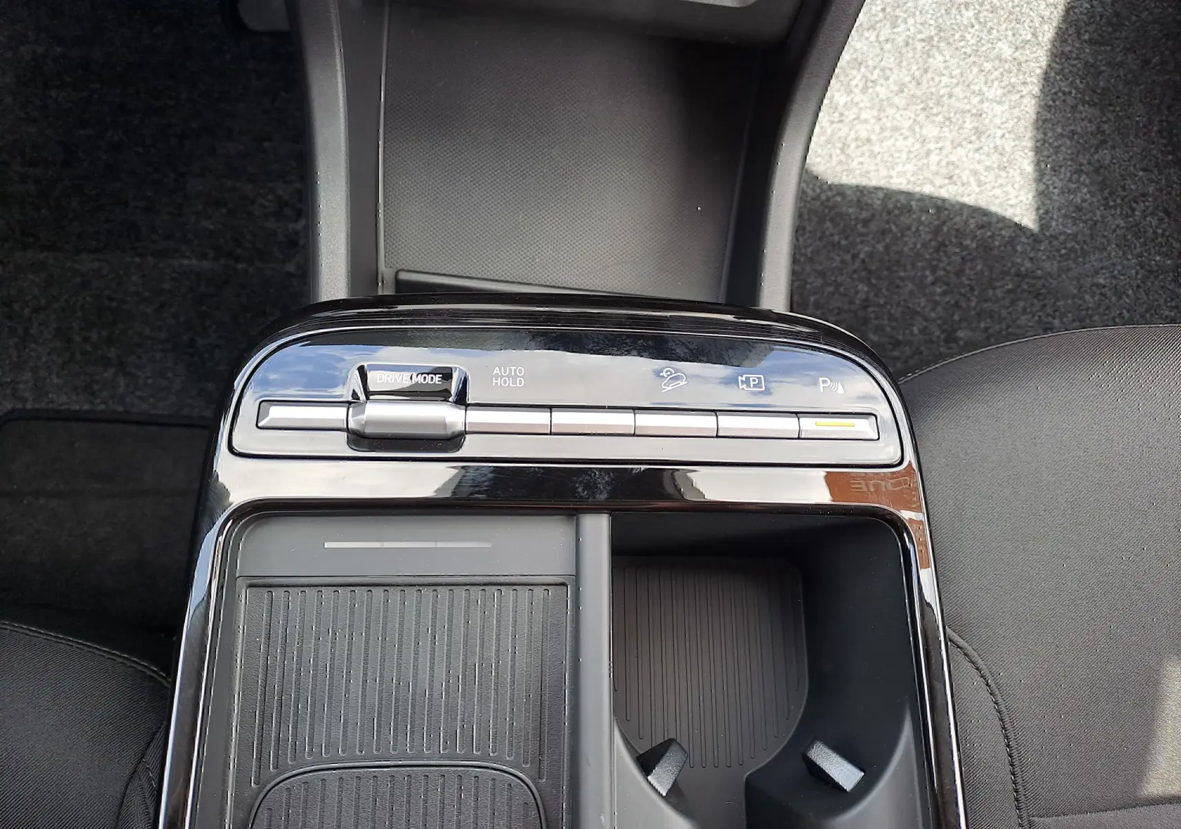 Gros plan sur la console centrale noire du Hyundai Tucson 2025 avec commandes de mode de conduite et porte-gobelets.