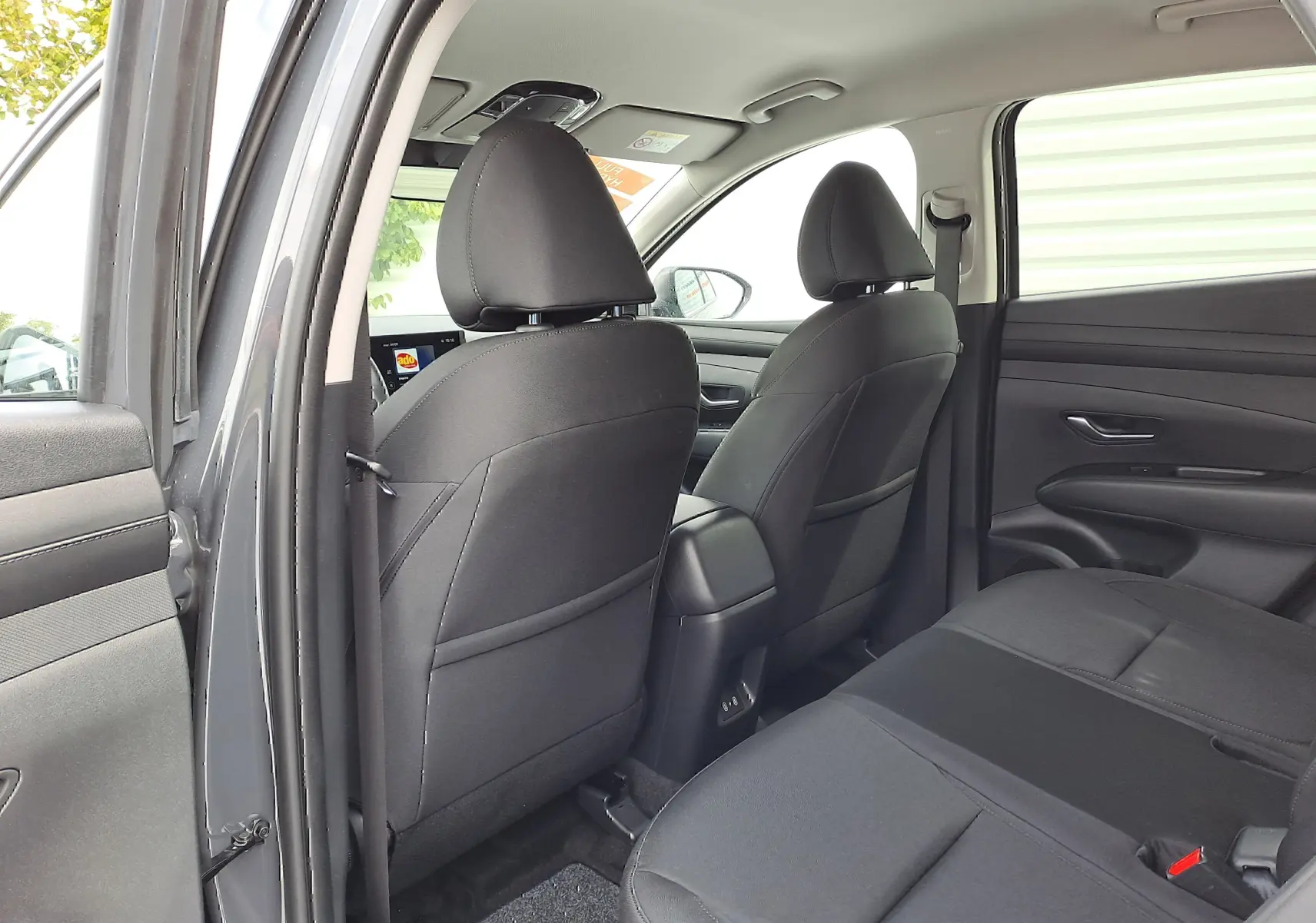 Vue intérieure arrière du Hyundai Tucson 2025 gris Ecotronic, sièges et garnitures en tissu noir avec console centrale visible.