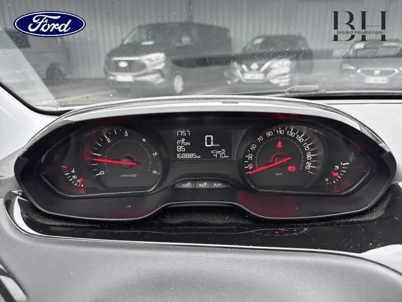 Tableau de bord de Peugeot 208 blanc Banquise, vue frontale centrée sur les compteurs numériques et analogiques.