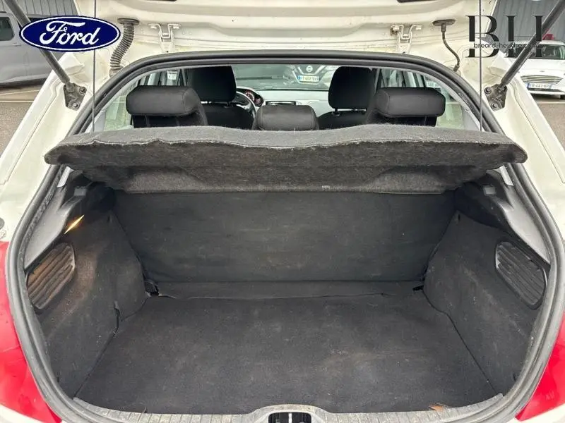 Coffre ouvert d'une Peugeot 208 blanc banquise, vue arrière montrant l'espace de chargement et la tablette cache-bagages.