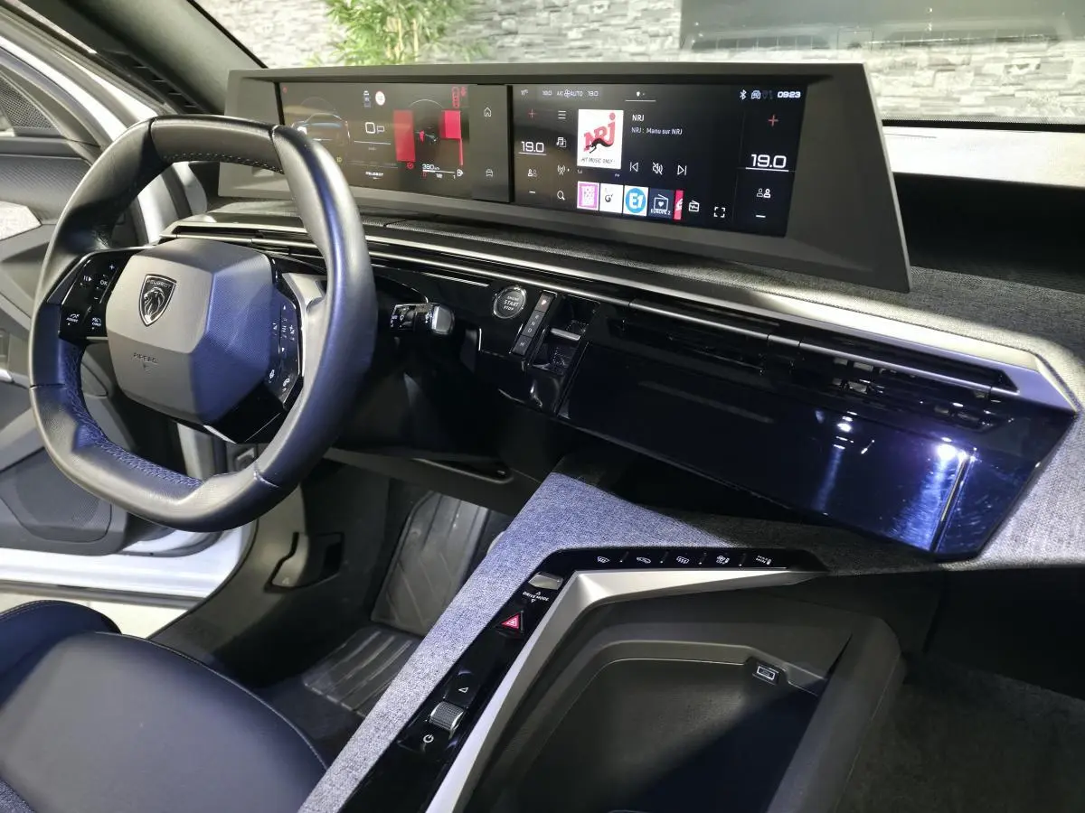 Vue intérieure côté conducteur du Peugeot 3008 blanc 2025, volant compact cuir et double écran HD panoramique.