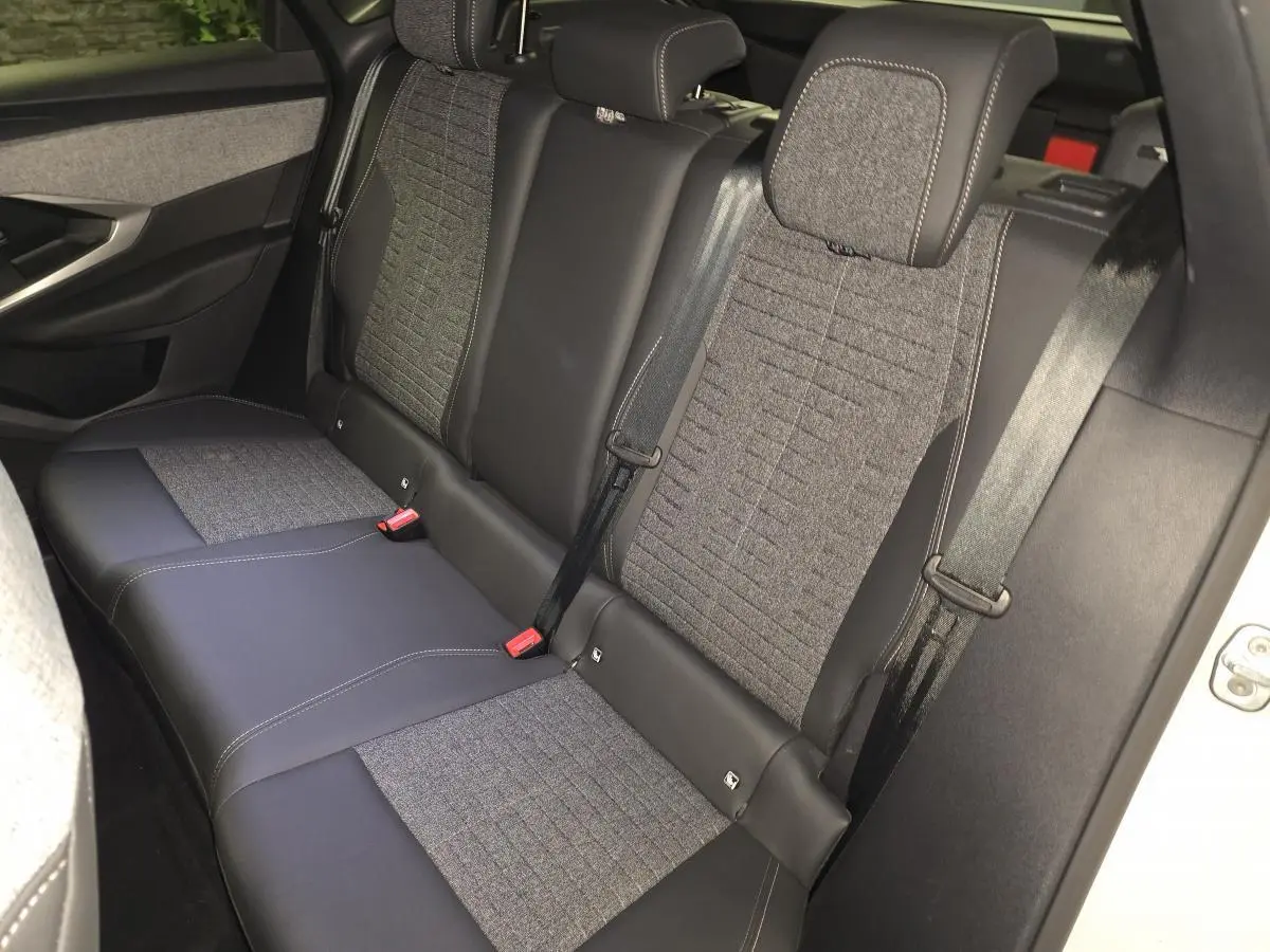Vue intérieure côté droit des sièges arrière gris tissu et cuir du Peugeot 3008 blanc 2025 hybride.