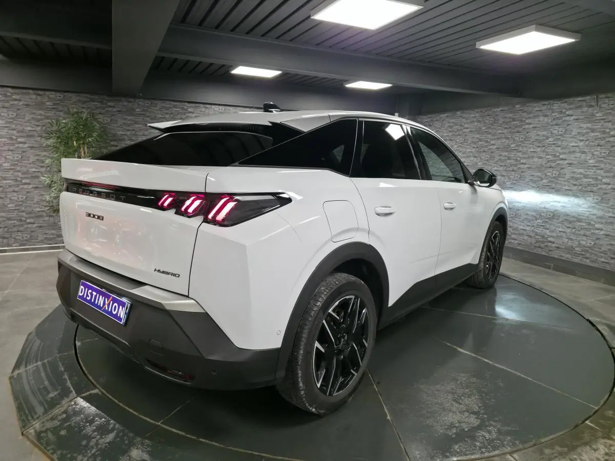 Vue 3/4 arrière droite du Peugeot 3008 hybride blanc avec feux arrière LED en forme de griffes et jantes alliage noires.