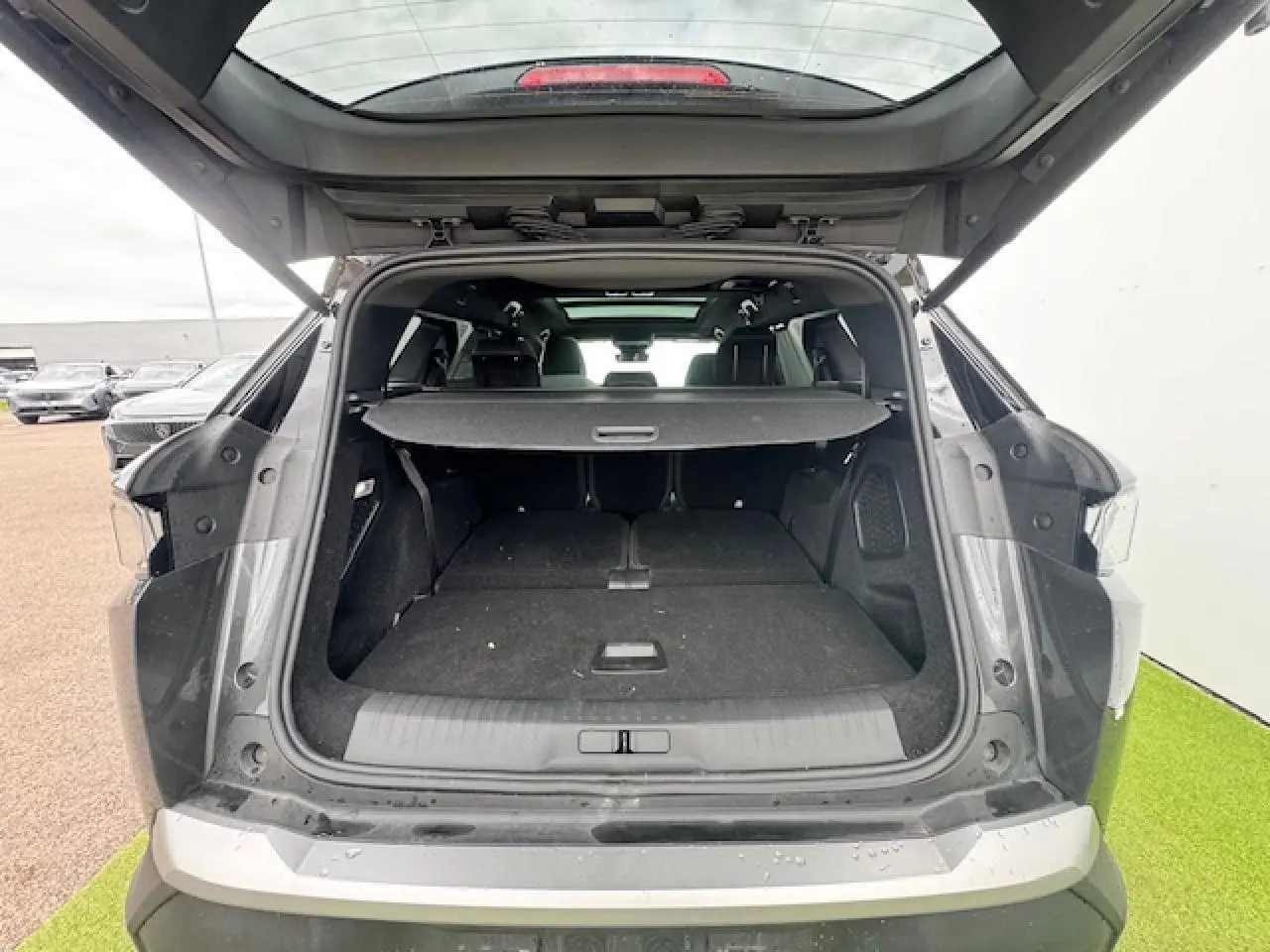 Coffre ouvert vue arrière d’un Peugeot 5008 gris titane avec toit noir, montrant l’espace de chargement et la plage arrière.
