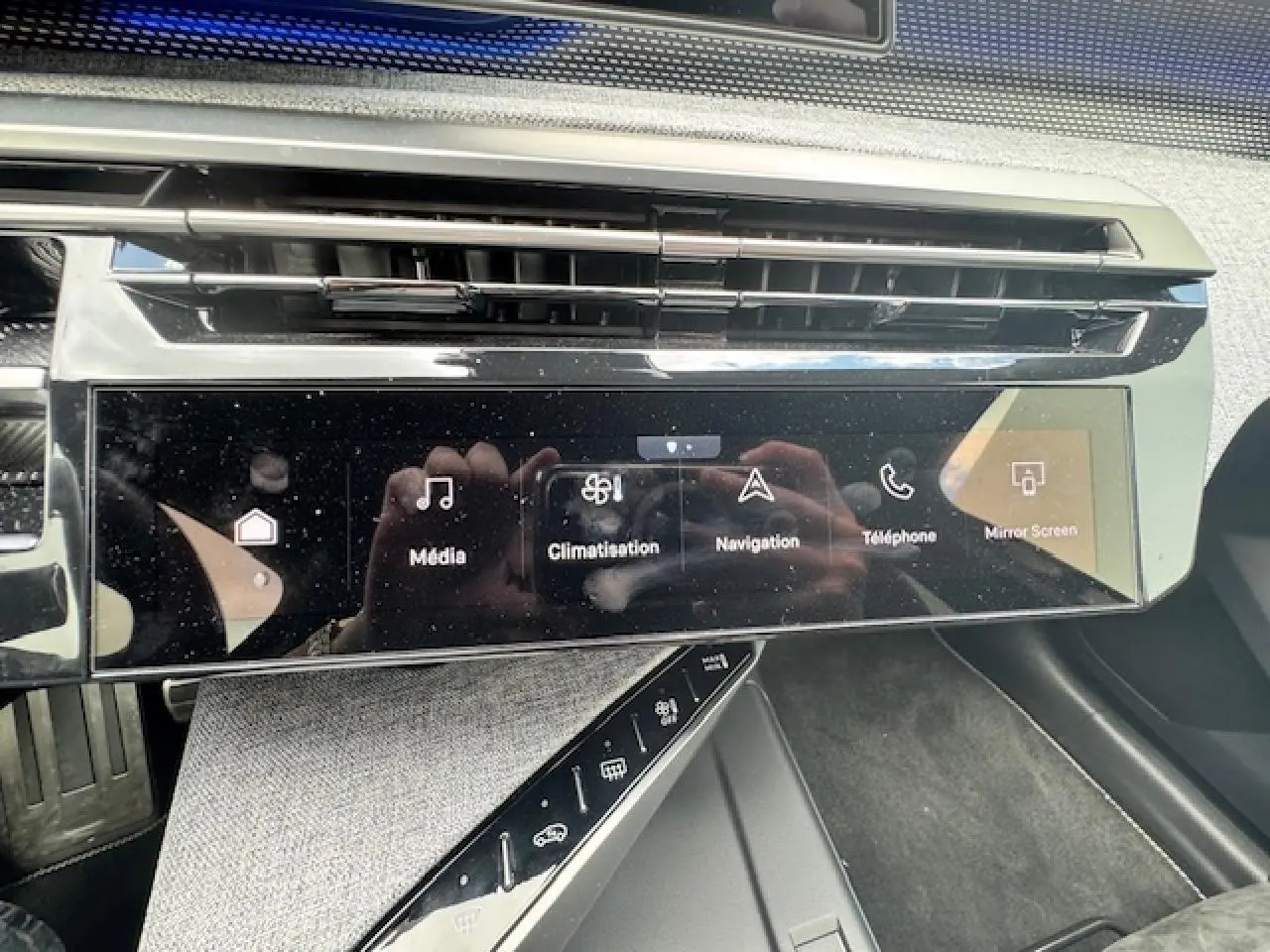 Écran tactile central du tableau de bord du Peugeot 5008 gris titane, avec commandes multimédia et climatisation visibles.
