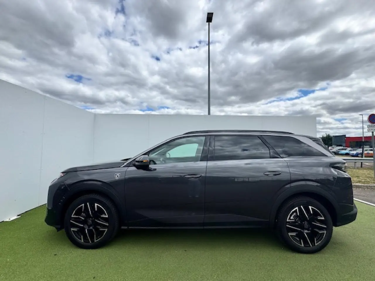 Profil côté gauche du Peugeot 5008 gris titane avec toit noir, jantes alliage 19 pouces et vitres teintées.