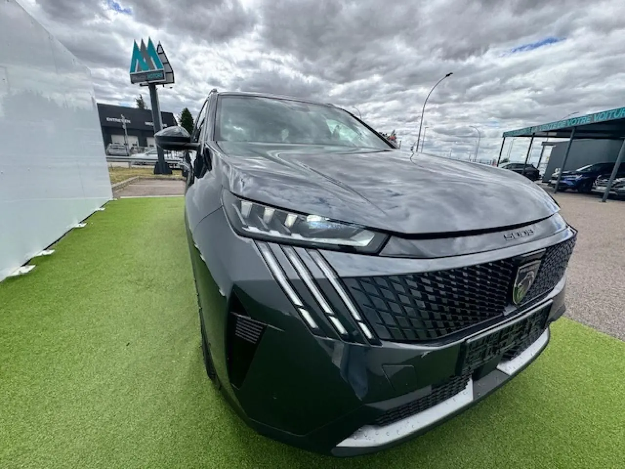 Vue 3/4 avant gauche d'un Peugeot 5008 gris titane avec toit noir et signature lumineuse à LED verticale.