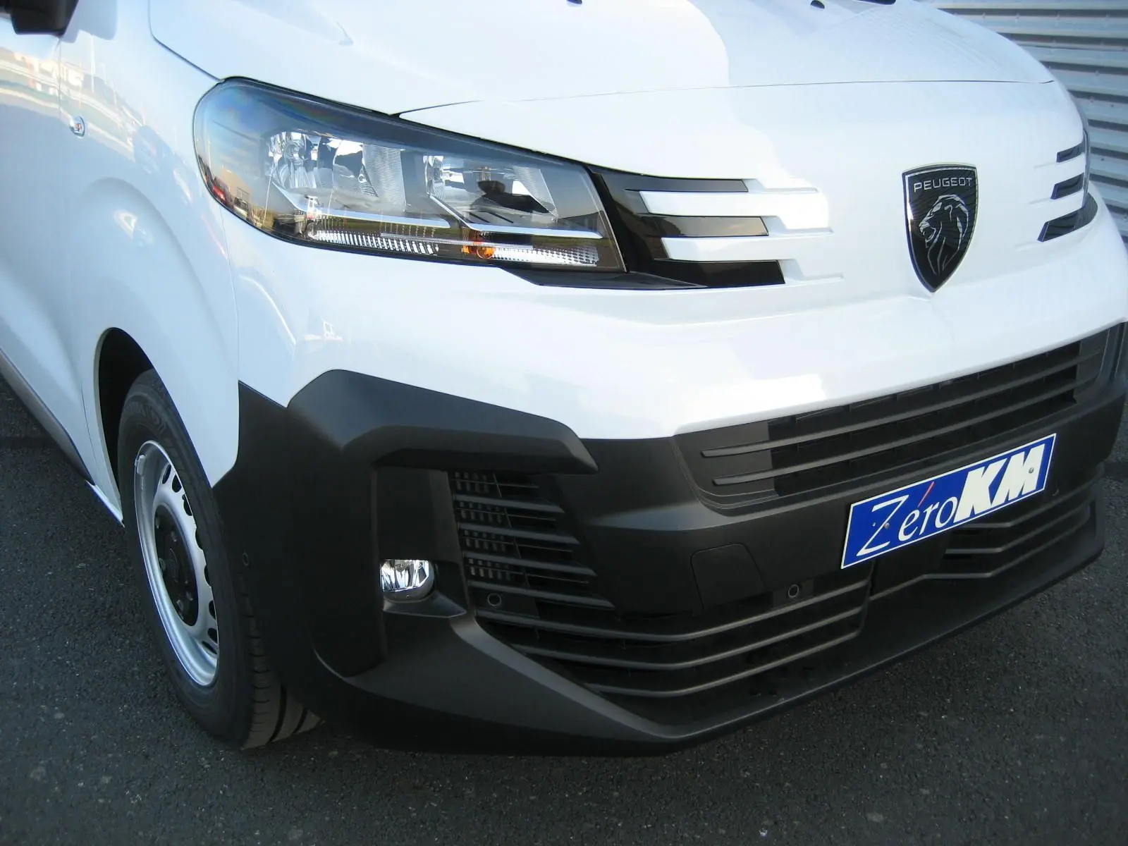 Gros plan sur l'avant droit blanc du Peugeot Expert Fourgon 2025 avec calandre noire et logo lion visible.