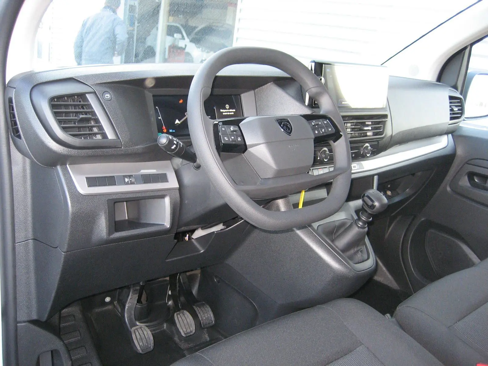 Intérieur du Peugeot Expert Fourgon 2025 montrant le tableau de bord et volant côté conducteur avec boîte manuelle.