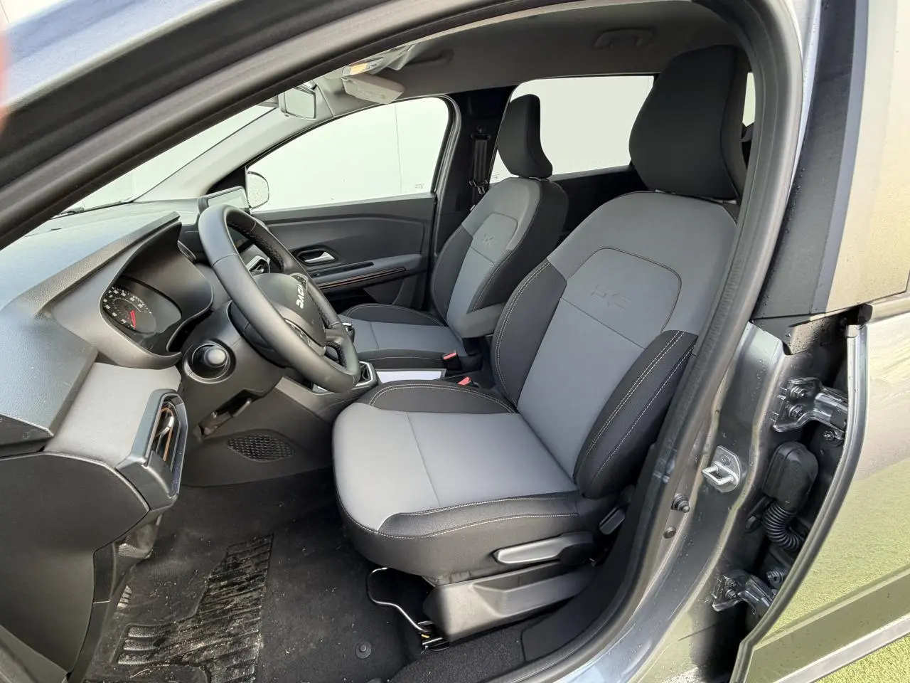 Vue intérieure côté conducteur du Dacia Jogger gris schiste métal 2025, avec sièges tissu bi-ton gris et noir.