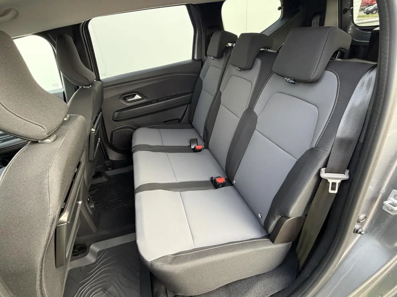 Vue intérieure côté droit sur la banquette arrière grise du Dacia Jogger 2025 avec sellerie mixte et ceinture de sécurité.