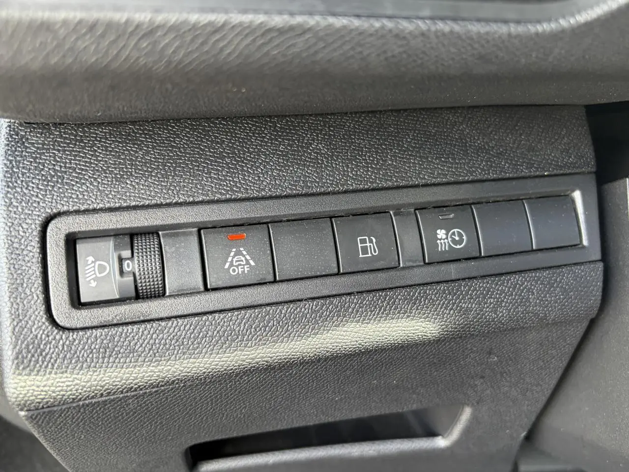 Gros plan sur les commandes noires du tableau de bord du Peugeot 3008 Plug-in Hybrid 2024, avec boutons d'assistance et réglages lumineux.