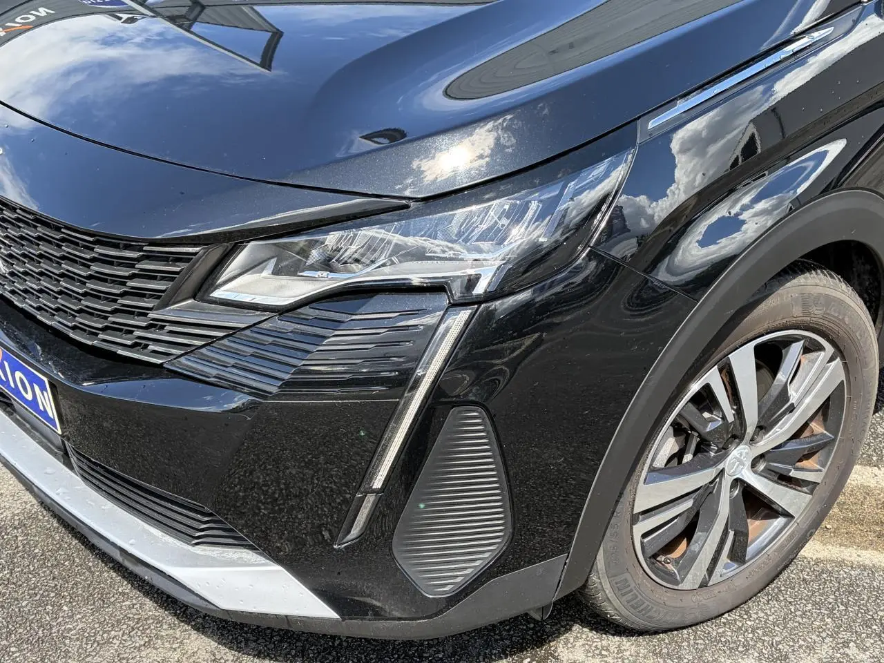 Gros plan sur l'avant droit noir Perla du Peugeot 3008 2024 avec projecteur LED et jante alliage bi-ton.