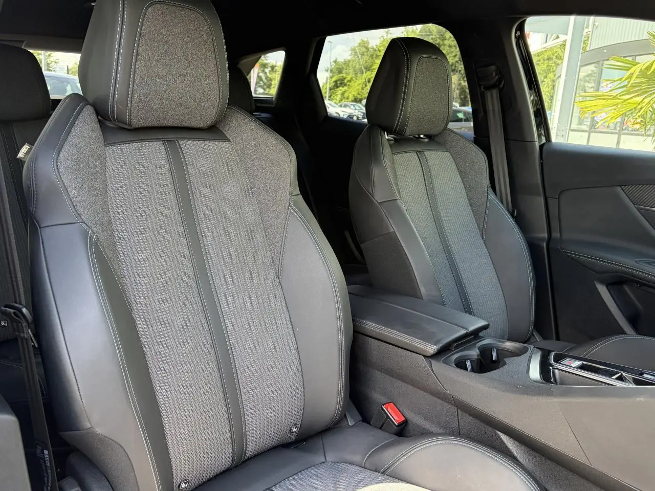 Vue intérieure sur les sièges avant gris tissu et cuir du Peugeot 3008 Plug-in Hybrid 2024 avec accoudoir central.