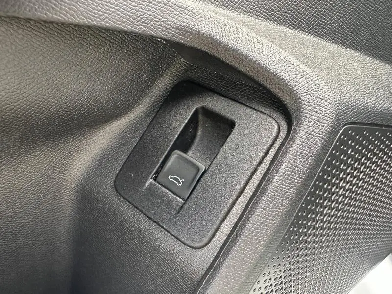 Gros plan sur le bouton d'ouverture du coffre dans l'habitacle noir d'une CUPRA Formentor blanc Nevada.