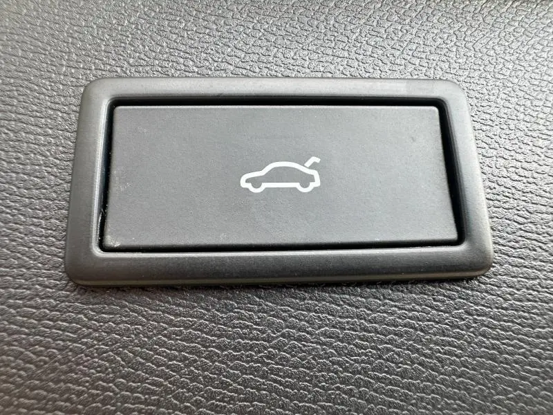 Bouton noir avec pictogramme blanc d'une voiture au coffre ouvert, situé sur la garniture intérieure du CUPRA Formentor.