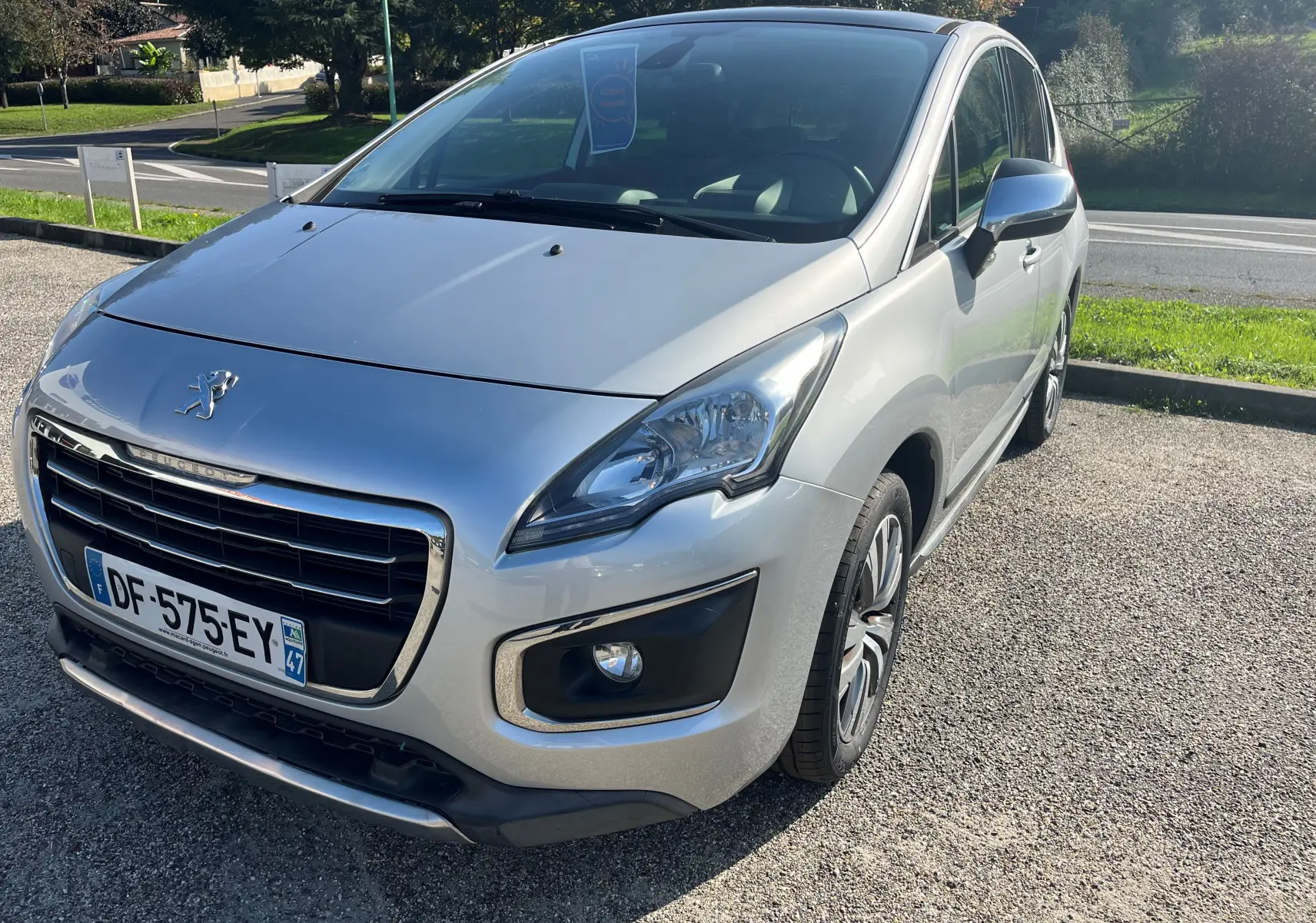 Peugeot 3008 gris clair vue 3/4 avant droit, mettant en valeur sa calandre chromée et ses phares distinctifs.