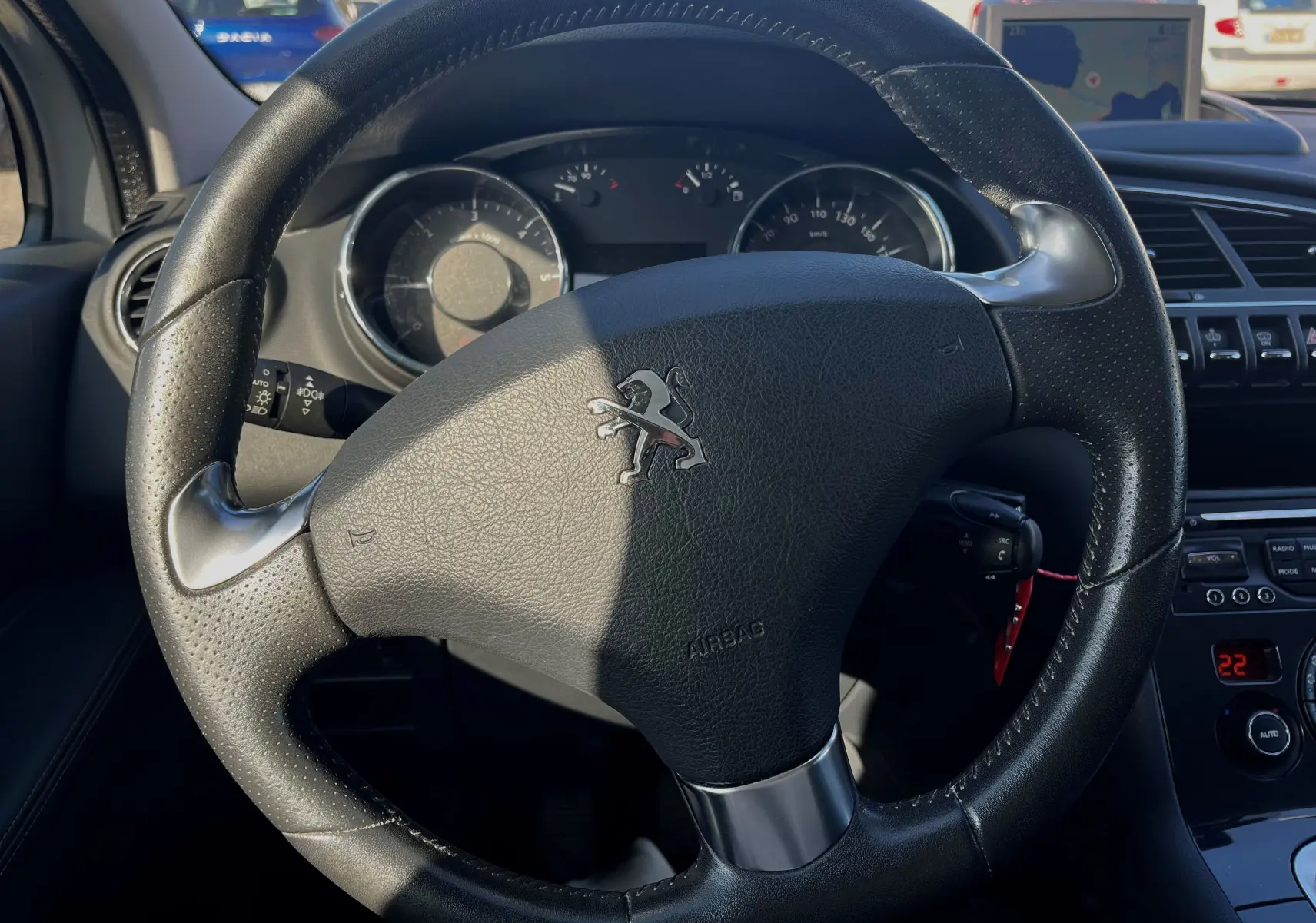 Volant en cuir noir avec logo Peugeot au centre, tableau de bord et commandes intérieures du Peugeot 3008 gris clair 2014.