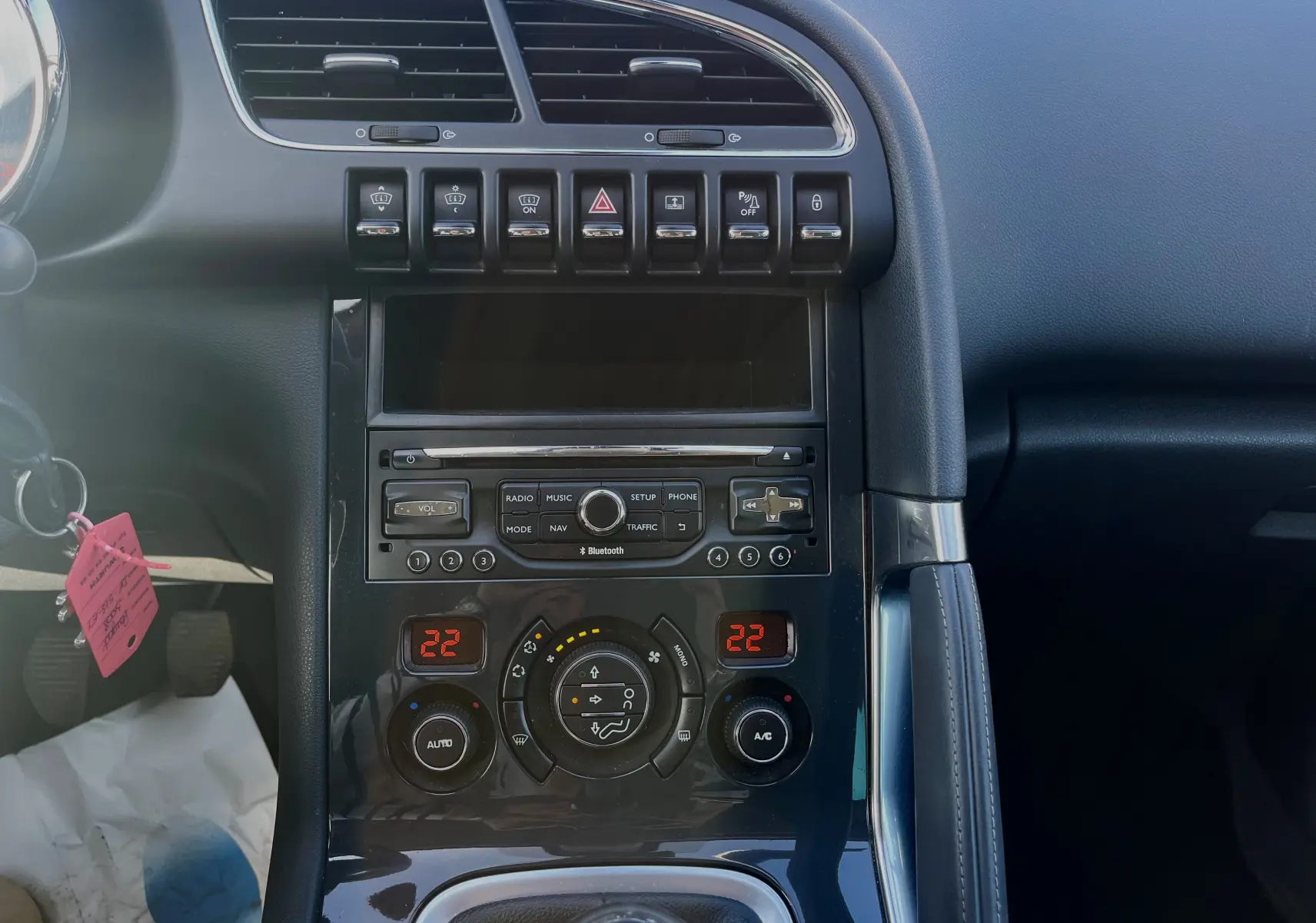 Vue rapprochée de la console centrale noire du Peugeot 3008 gris clair, avec commandes climatisation et radio visibles.