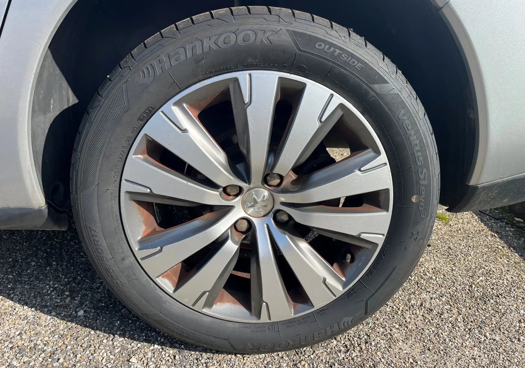 Gros plan sur la roue avant droite d’un Peugeot 3008 gris clair de 2014 avec jante alliage et pneu Hankook.