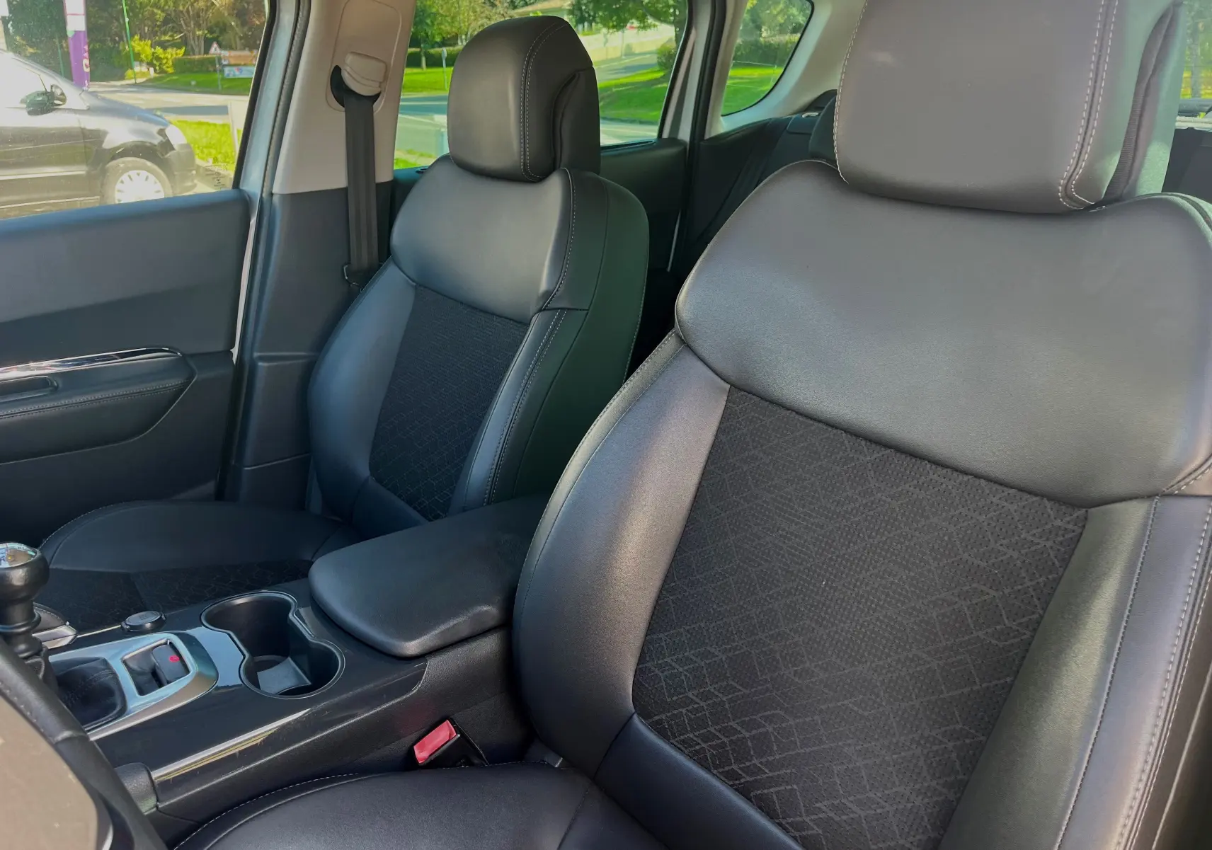 Vue intérieure rapprochée des sièges avant en cuir noir du Peugeot 3008 gris clair, avec console centrale et levier de vitesses manuel.