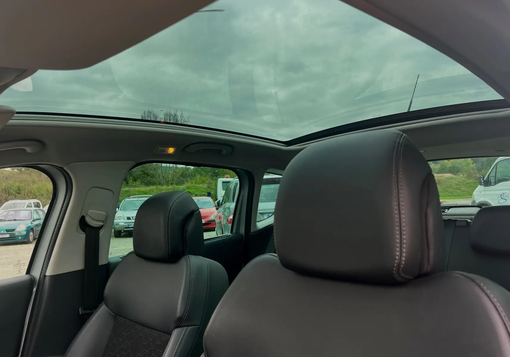 Vue intérieure du Peugeot 3008 2014 montrant les sièges avant en cuir noir et le toit panoramique ouvrant.