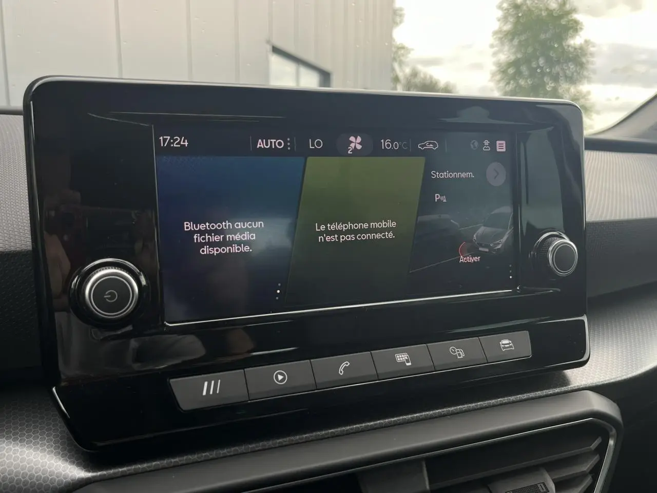 Écran tactile central du tableau de bord du SEAT Leon 2024 noir Minuit, affichant les options de connectivité et de stationnement.
